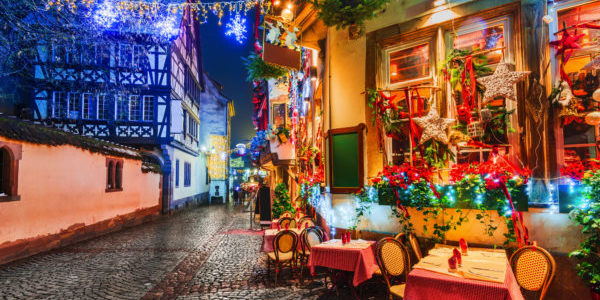 Strasbourg, France. Street cafe tables on winter street, Christmas time. Alsace night scene with highlighted old buildings in tourisitic concept.